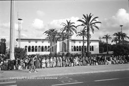 Image du Maroc Professionnelle de  Tout un peuple hommes, femmes, enfants de tous âges était là, assis sur le muret qui clôture le jardin situé juste en face de la wilaya de Casablanca. Ce beau monde attend passionnément le départ de la fontaine lumineuse, Vendredi 10 Août 1984. A l’époque au début du siècle dernier (20e) on a planté des palmiers ainsi que d’autres végétaux pour réduire l’angoisse de tous ceux qui ont une affaire au Palais de Justice. (Photo / Abdeljalil Bounhar) 